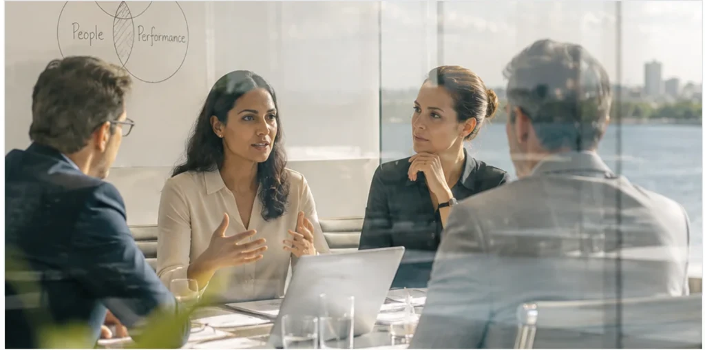 A facilitator and participants discussing leadership priorities around a meeting table.